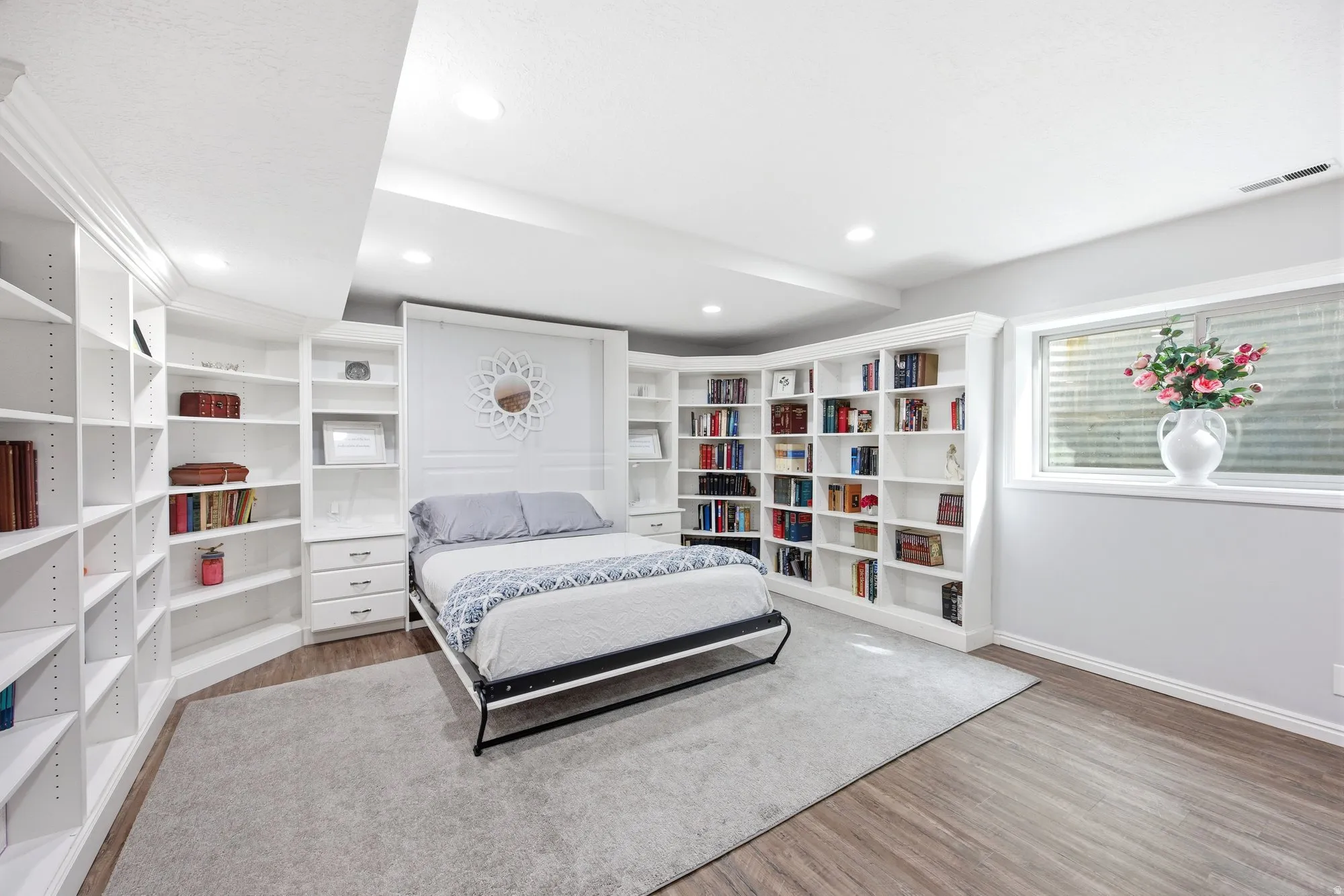 Studio  apartment library/bedroom, murphy bed with light wood-type flooring and recessed lighting