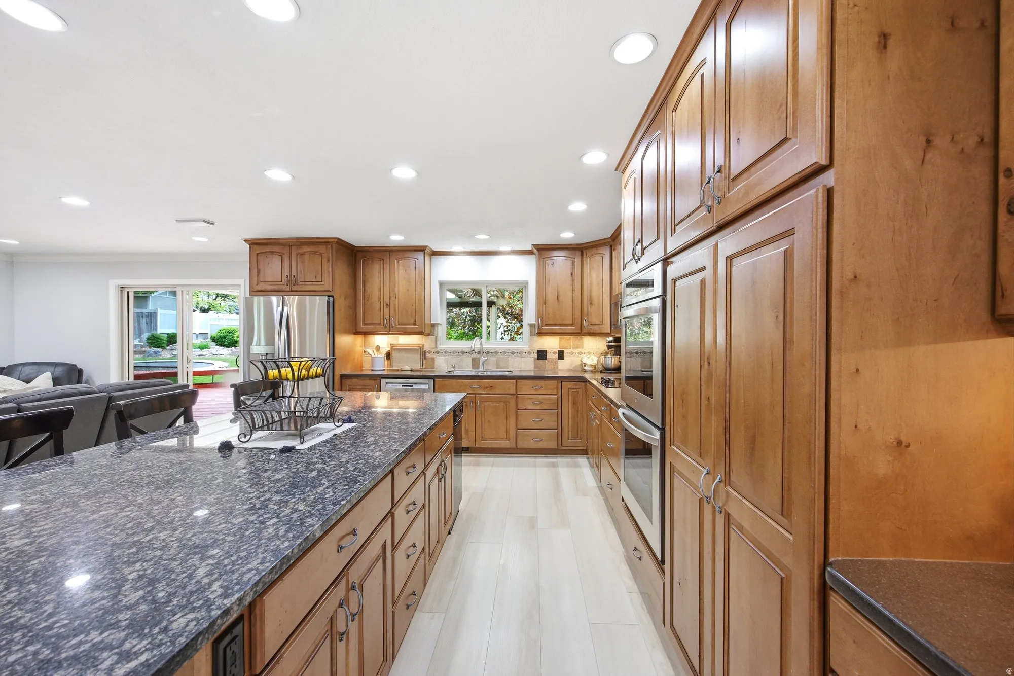 Kitchen featuring a large island and  bar area, and ceiling to floor custom cabinetry, stainless steel appliances, and under cabinet lighting.
