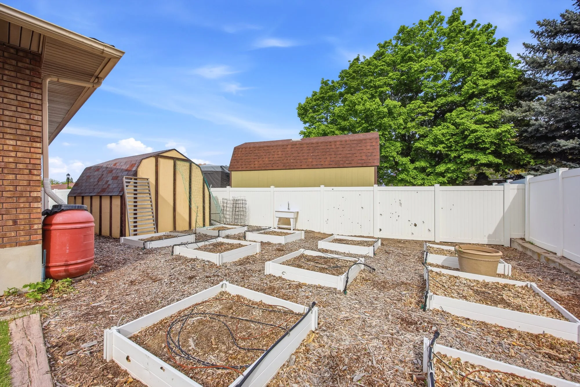 Fenced backyard with a storage unit and a garden