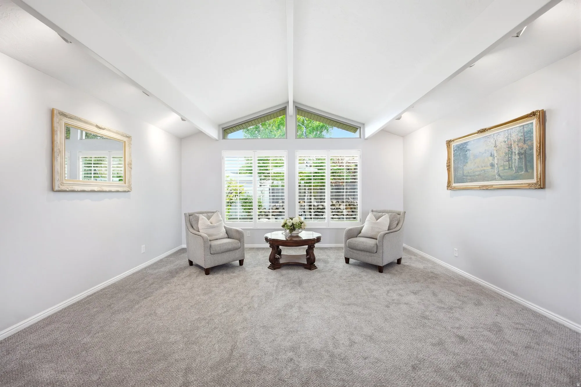 Large living area featuring a wall of windows for abundant natural light, beam ceiling, light colored carpet