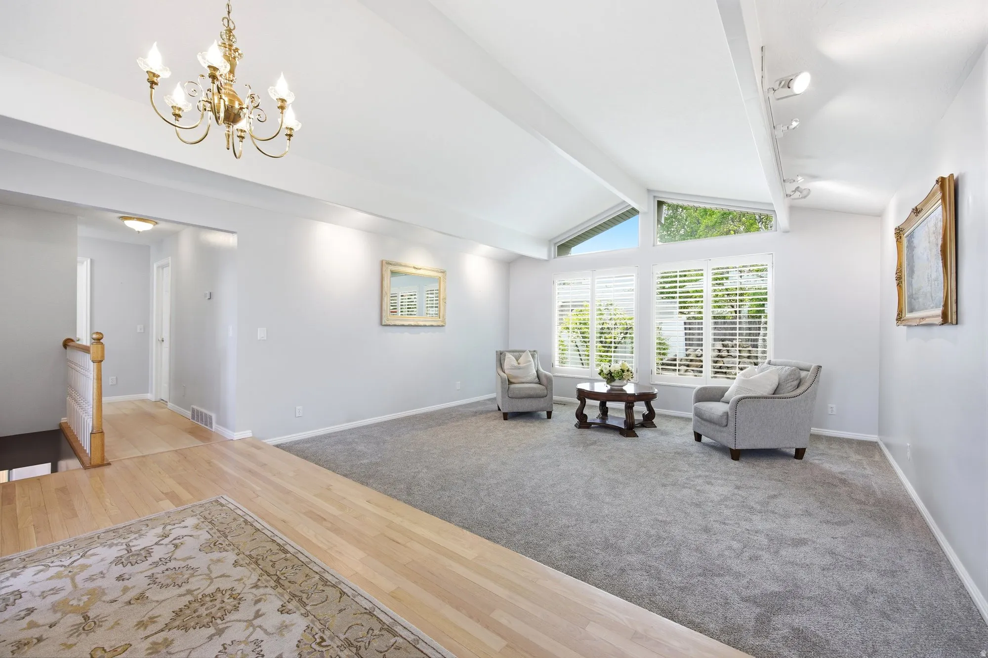 Large living area featuring a wall of windows for abundant natural light, beam ceiling, light colored carpet