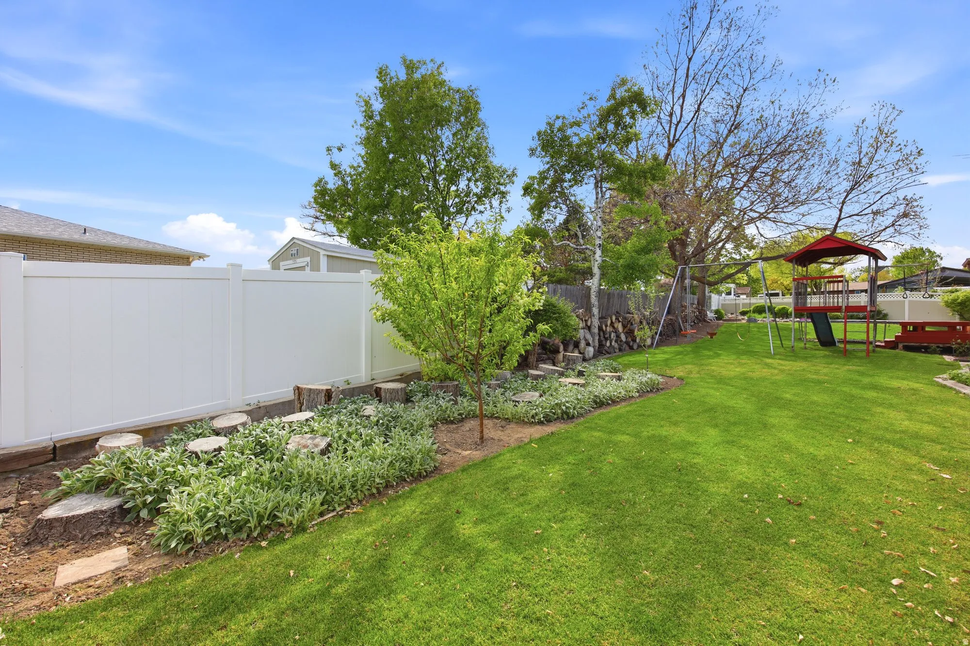 Fenced backyard featuring a playground and a garden