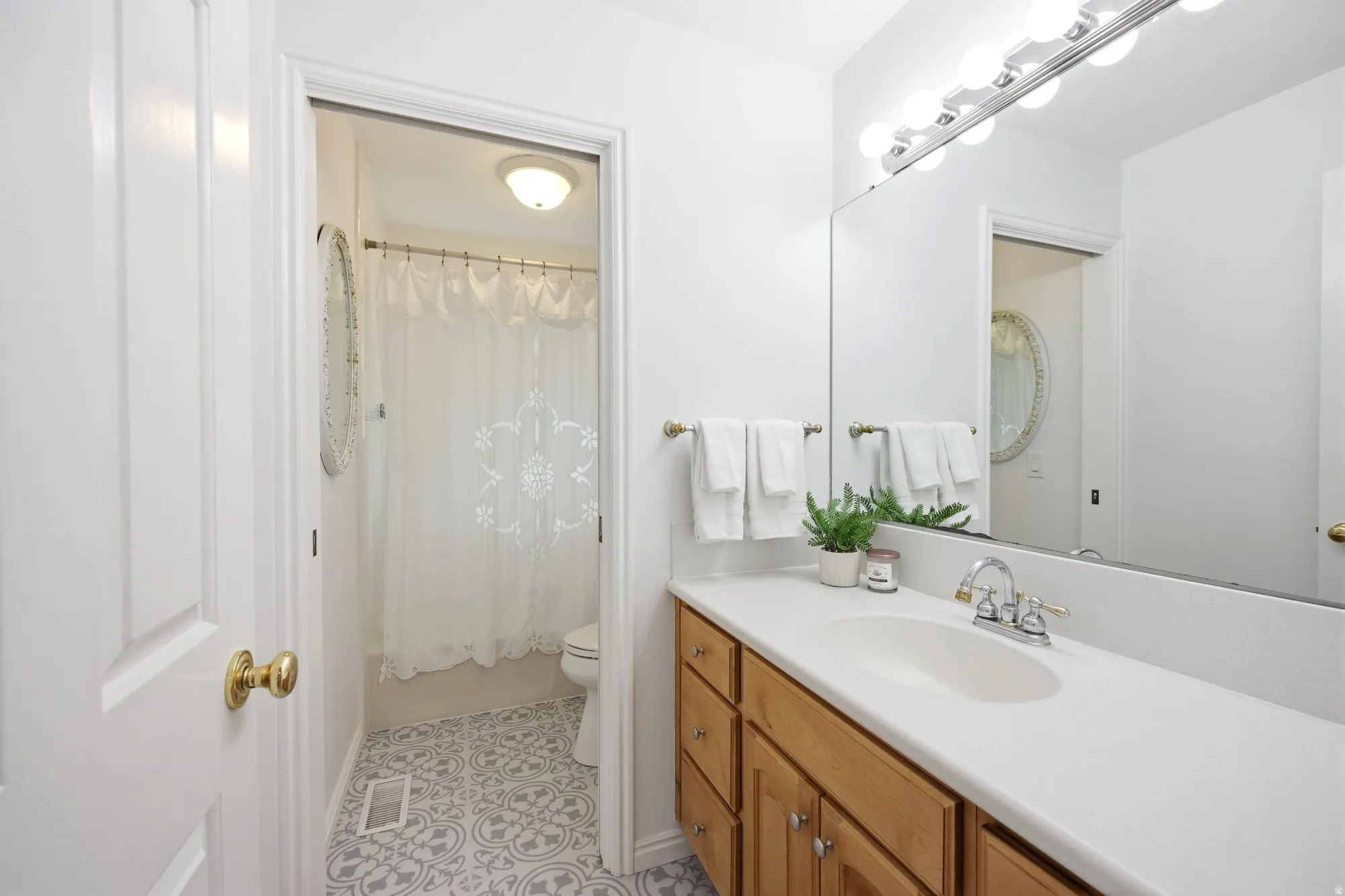 Full hallway  upstairs bathroom with vanity, shower / tub combo with curtain, and light tile patterned flooring