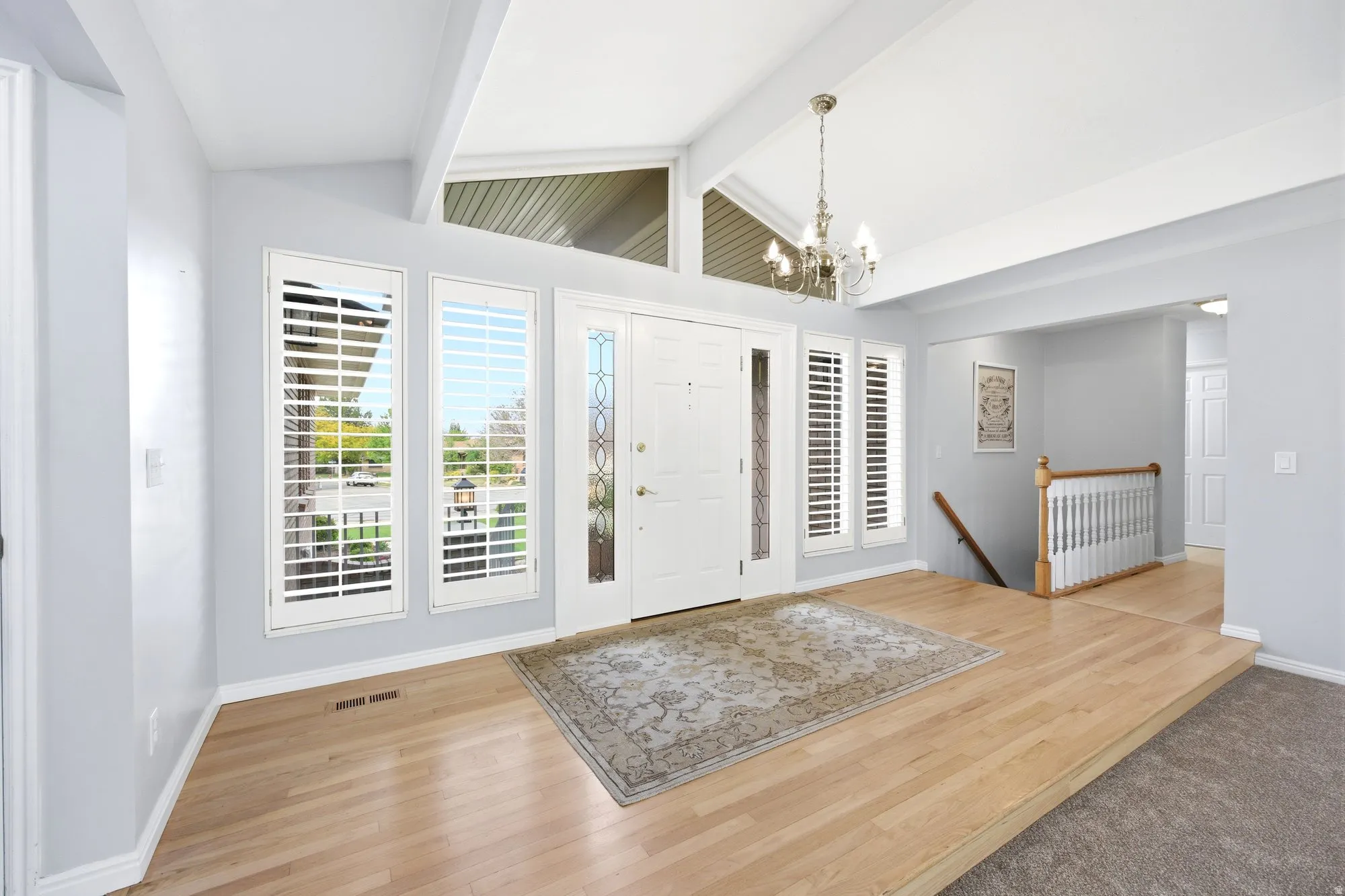 Entryway featuring ample windows for lots of natural light, beamed ceiling, and light solid hard wood floors
