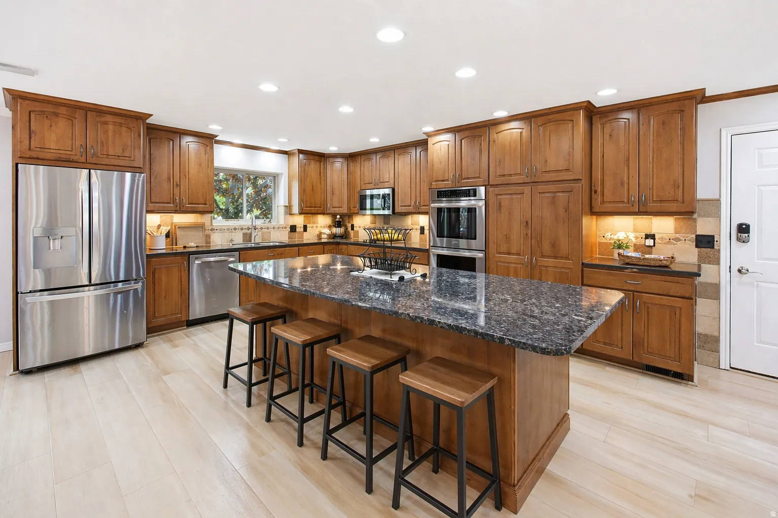 Kitchen featuring a large island bar area,  seats six, ceiling to floor custom cabinetry, stainless steel appliances, and under cabinet lighting.