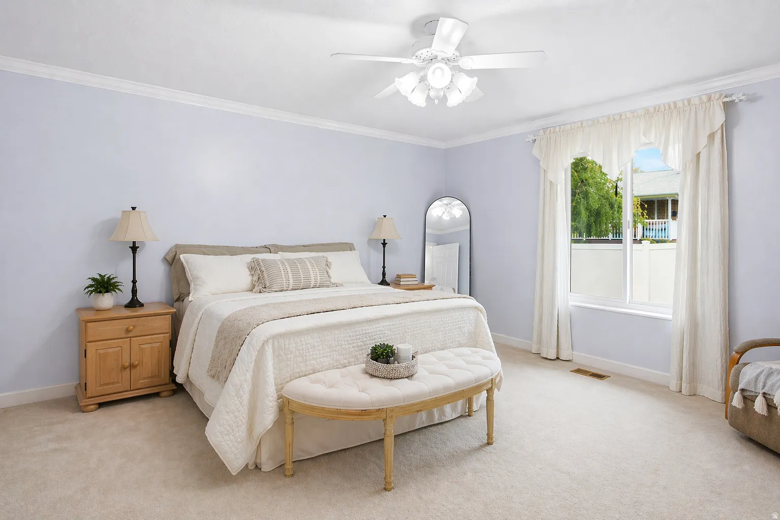 Huge primary bedroom with ornamental molding, light colored carpet, lots of natural light and a ceiling fan