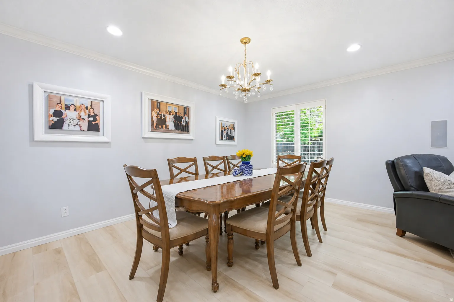 Dining space with light wood-type flooring, a chandelier, and crown molding