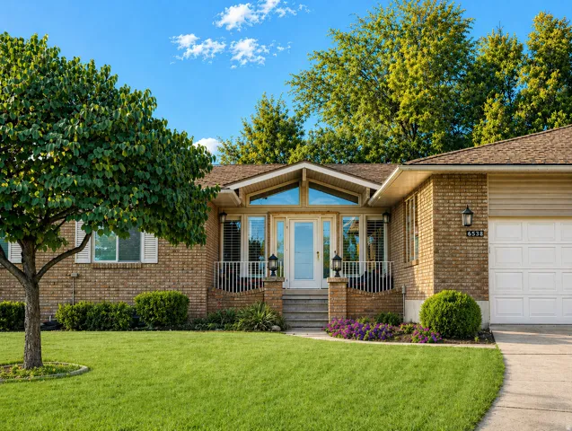 View of front facade with a front lawn, brick siding, a shingled roof, a porch, and an attached garage