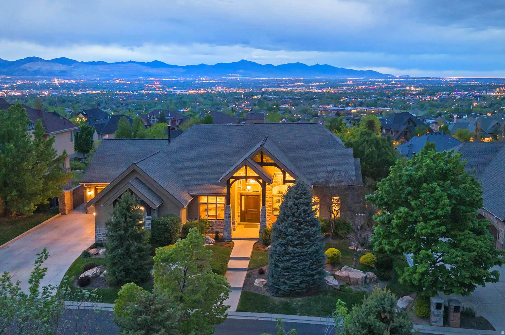 View of front facade with a mountain view, a shingled roof, stone siding, and driveway