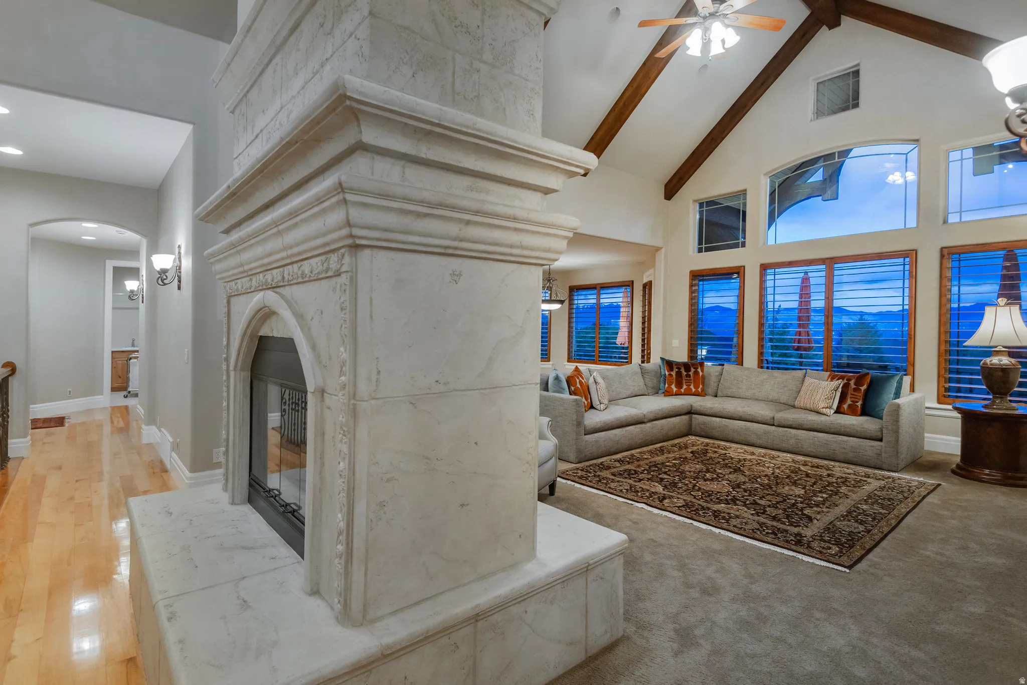 Living area with ceiling fan, vaulted ceiling, and arched walkways