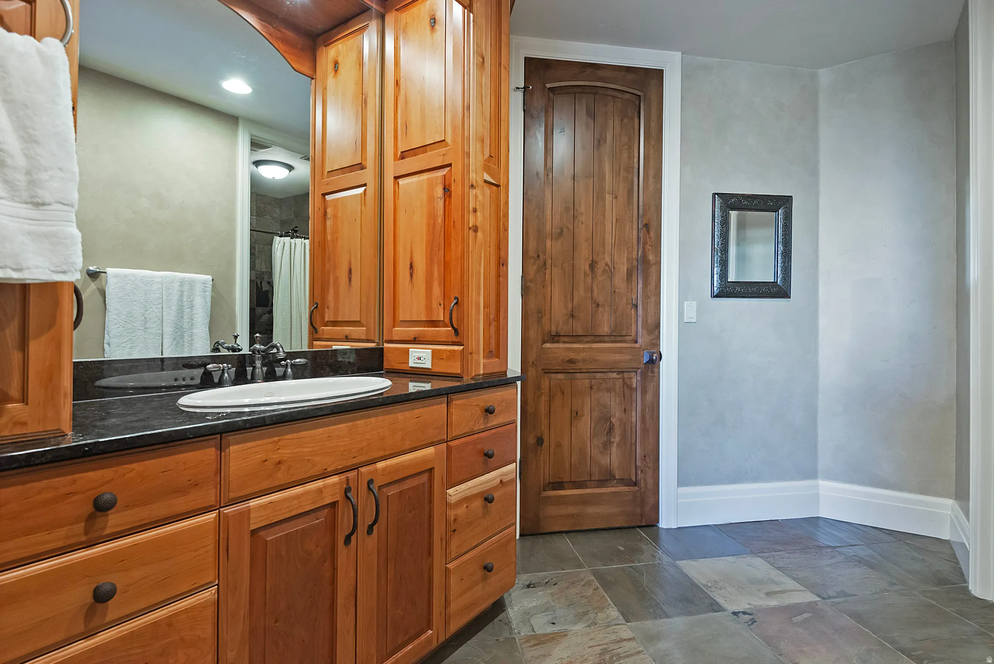 Full bathroom featuring vanity, a shower with curtain, and dark stone finish floors