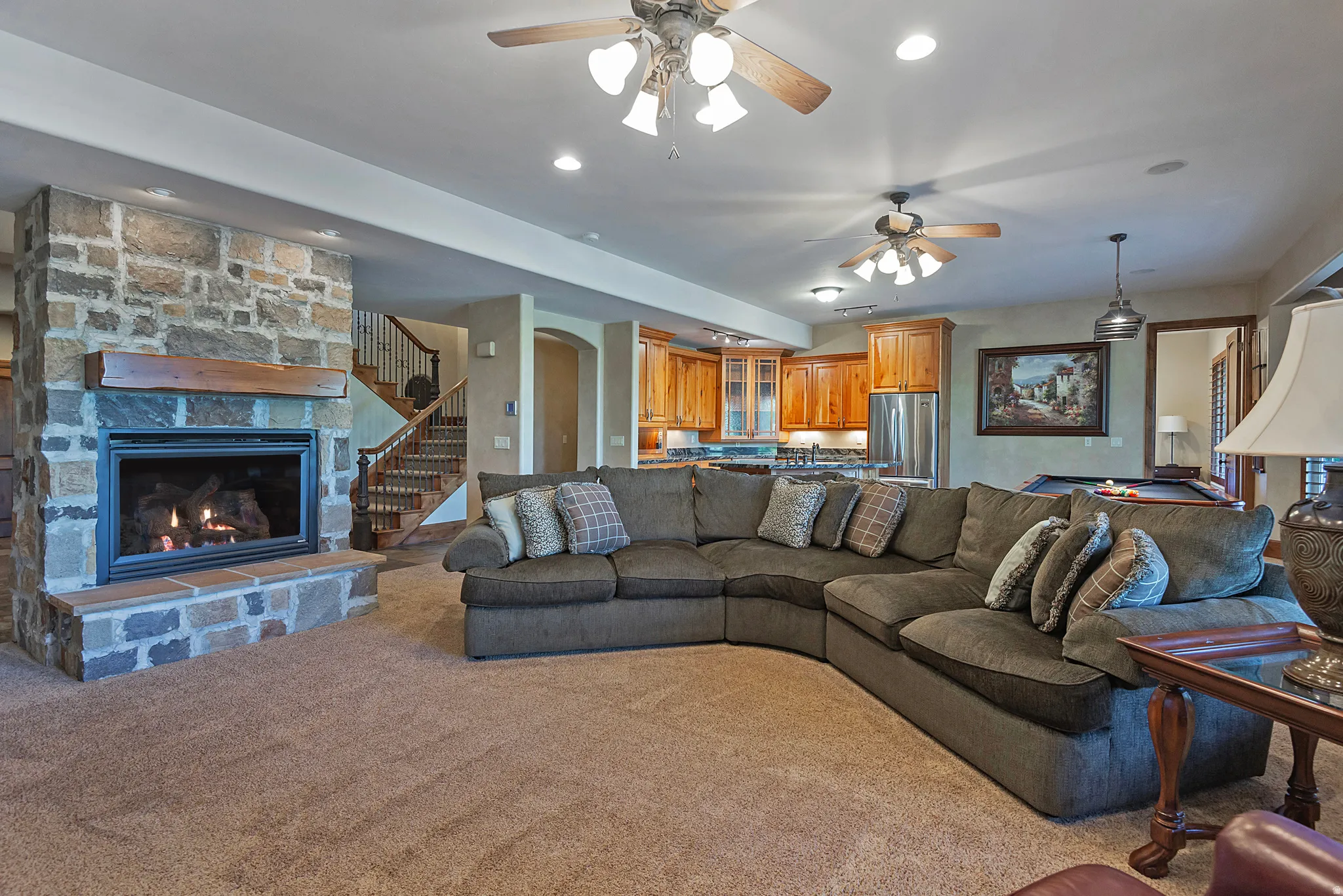 Living area featuring arched walkways, ceiling fan, a fireplace, carpet floors, and pool table