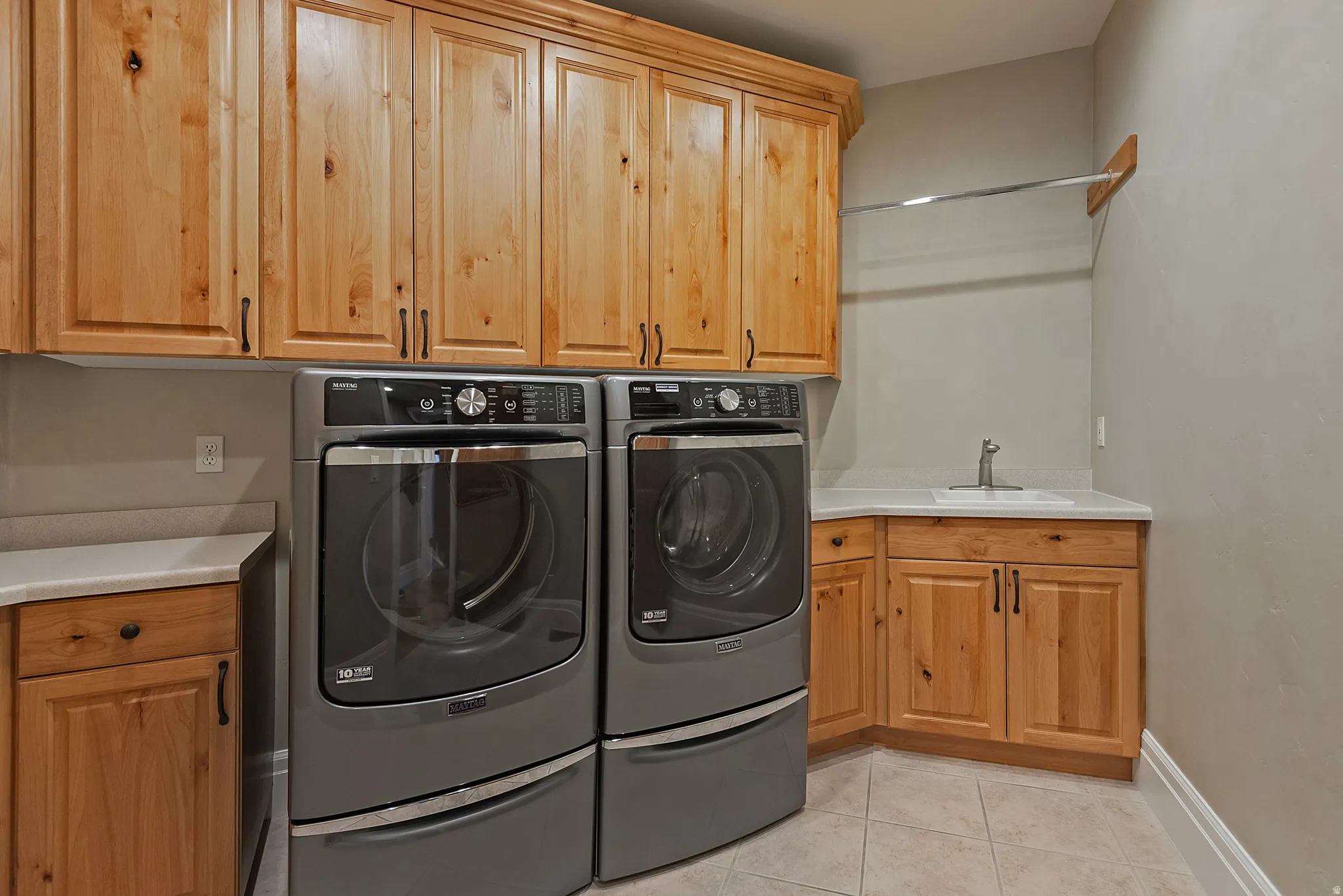 Laundry area featuring light tile patterned flooring, washing machine and dryer, and cabinet space