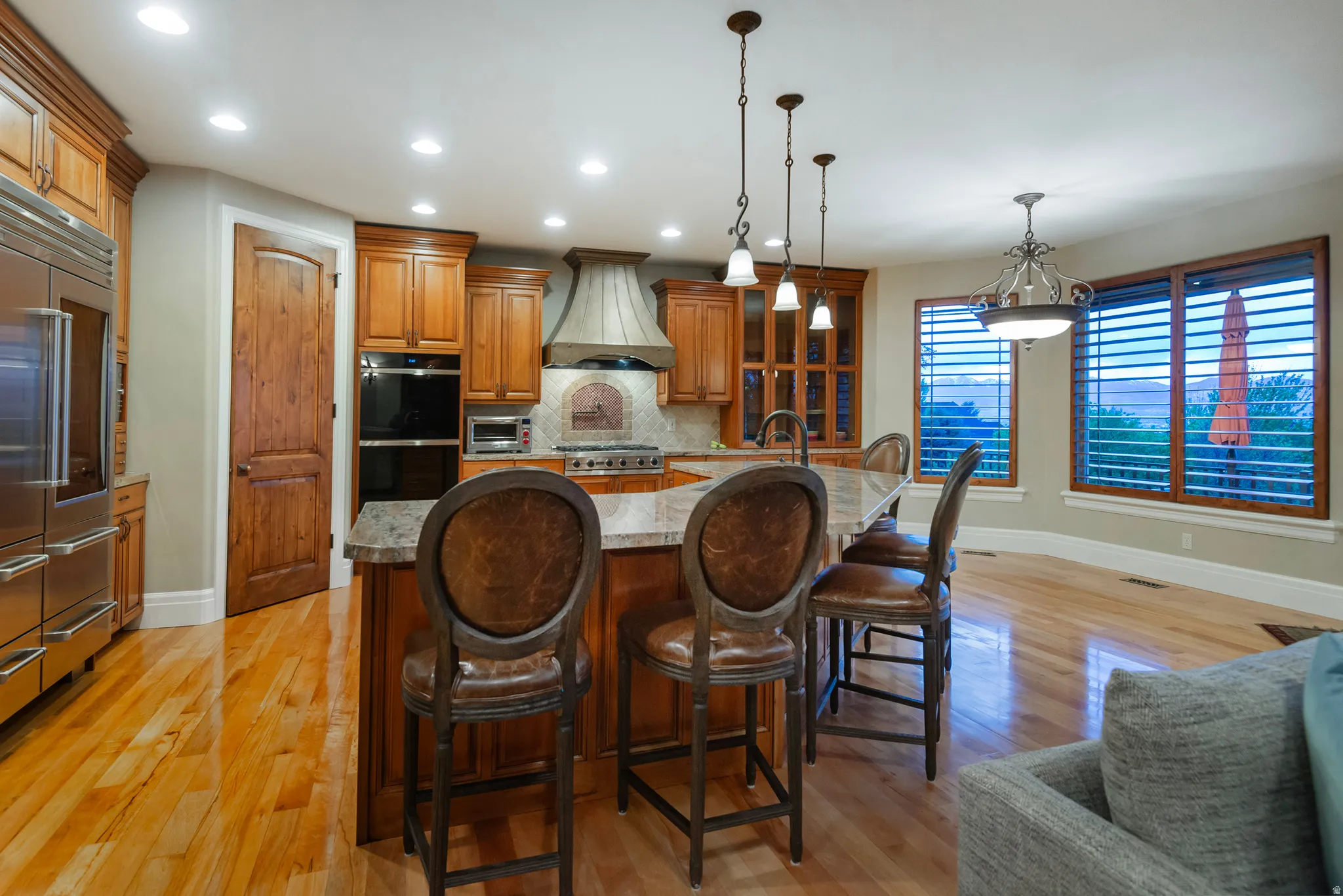 Kitchen featuring wood finish cabinets, a kitchen bar, a kitchen island with sink, light wood-style floors, and decorative light fixtures