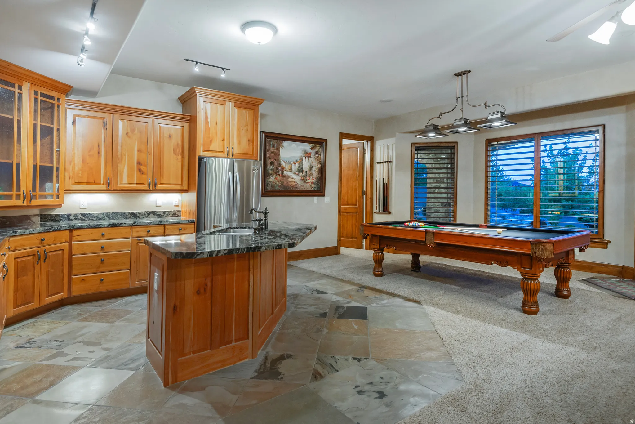 Kitchen with glass insert cabinets, wood finish cabinetry, billiards, freestanding refrigerator, and a kitchen island