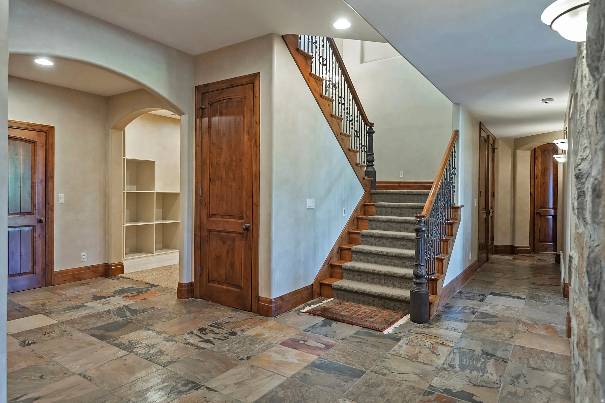 Staircase featuring arched walkways, stone tile floors, and recessed lighting