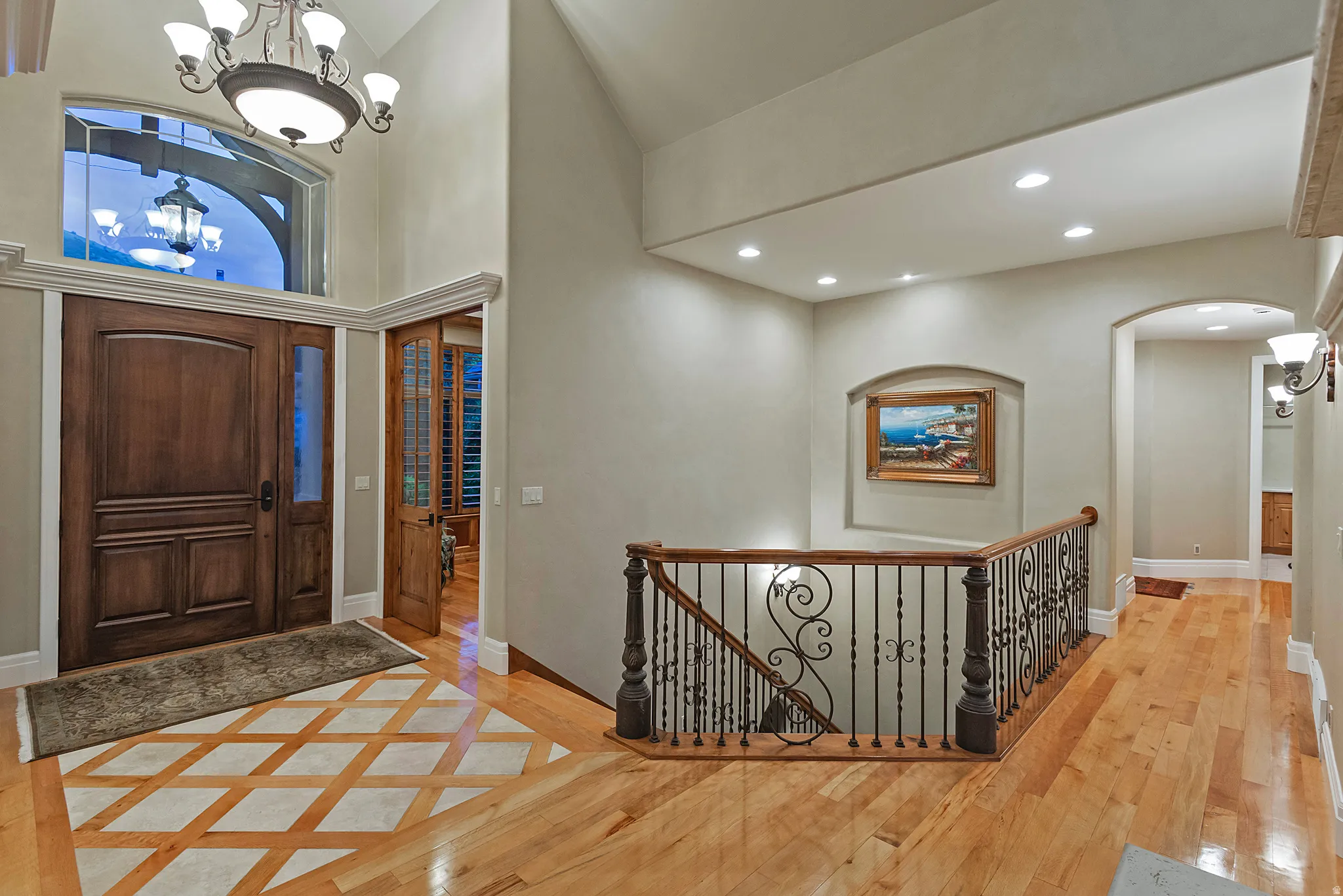 Foyer entrance featuring hanging lights, a high ceiling, light wood-style floors, and arched walkways
