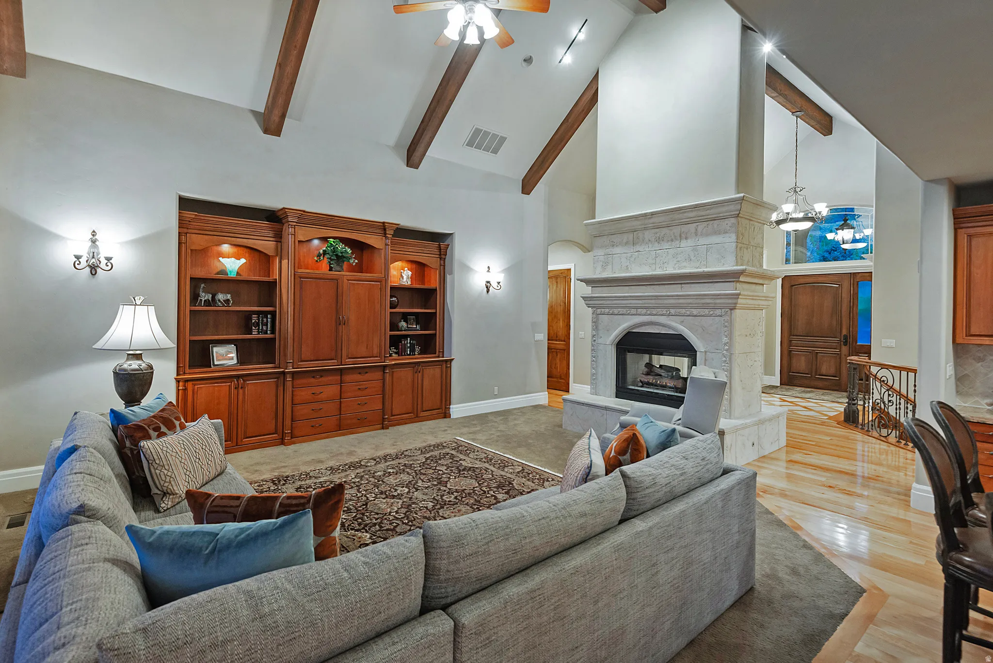 Living room with vaulted ceiling, a fireplace, ceiling fan, and a chandelier