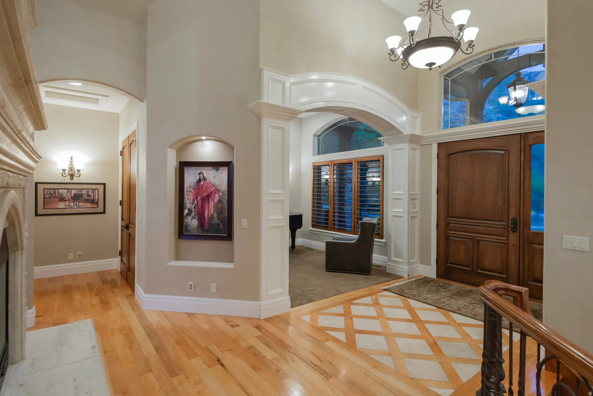 Entrance foyer with a high ceiling, hanging lights, arched walkways, light wood-type flooring, and inlaid floor details