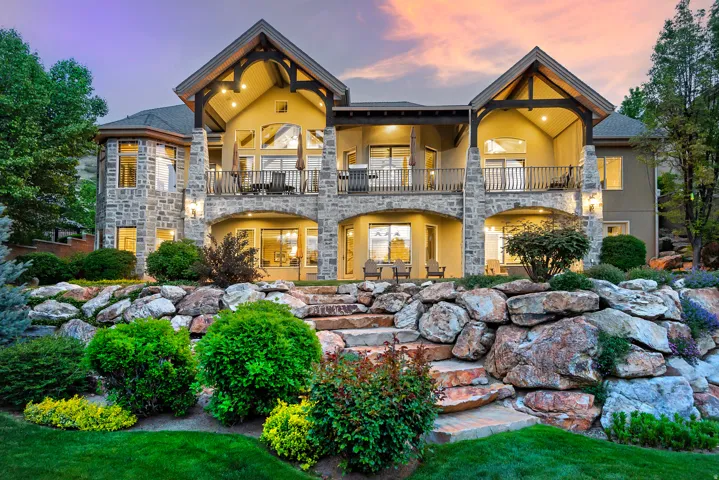 Back of property with stone siding, stucco siding, and a balcony