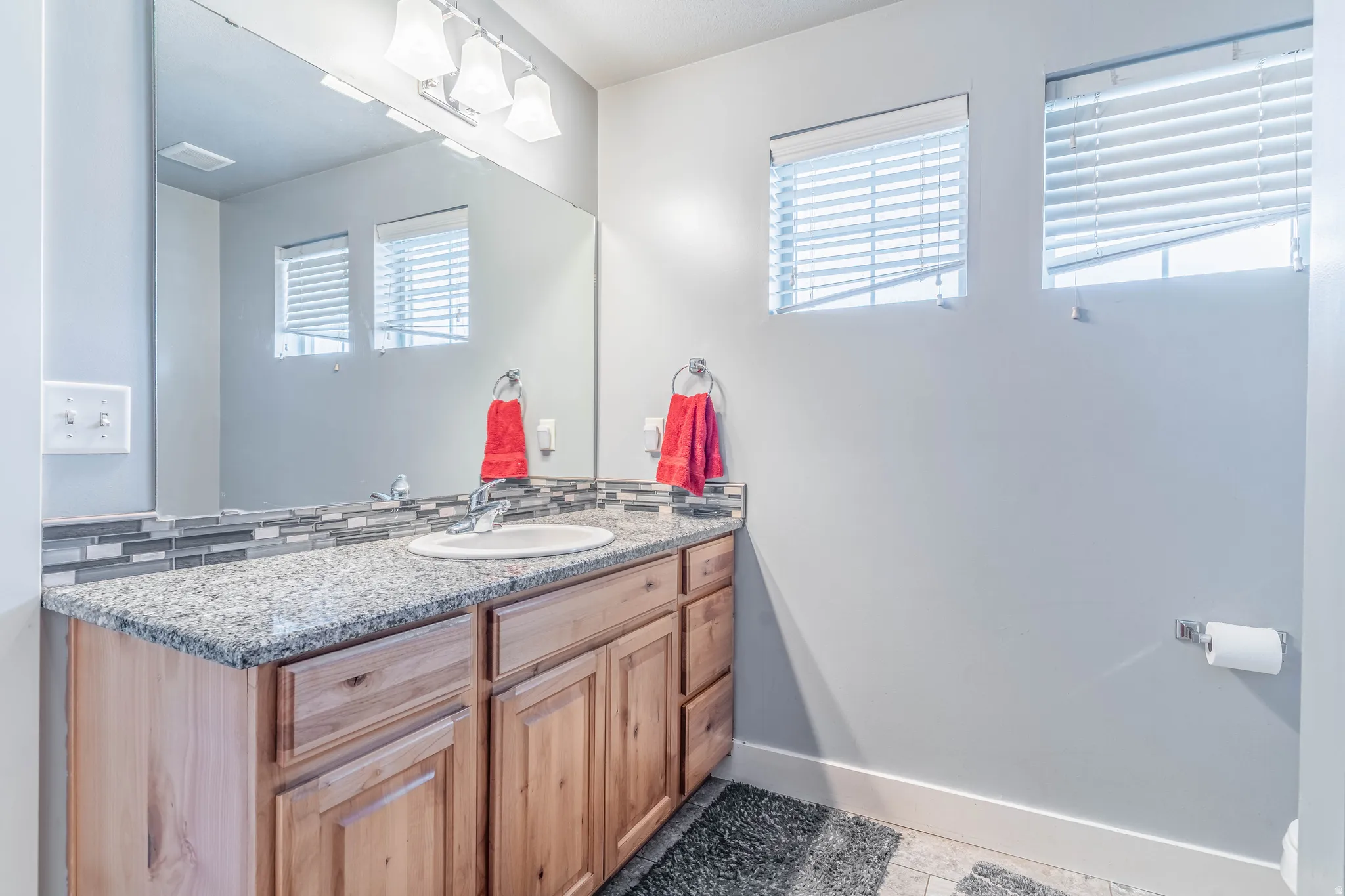 Bathroom featuring vanity, light tile patterned floors, and tasteful backsplash