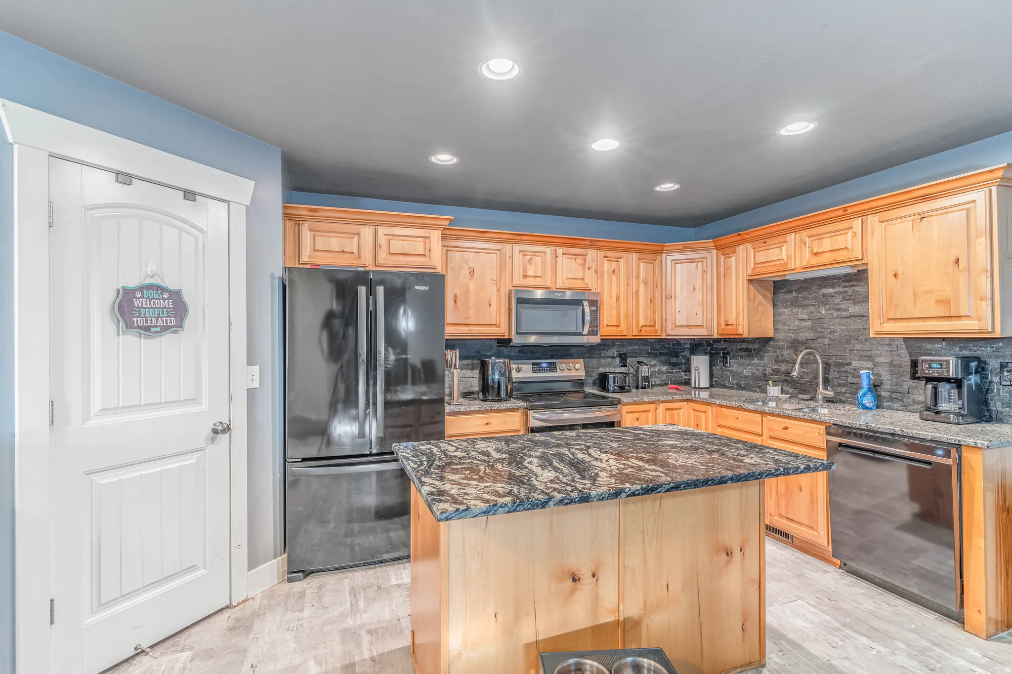 Kitchen with dark stone counters, stainless steel appliances, recessed lighting, backsplash, and a kitchen island