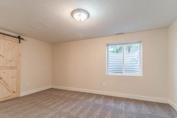 Unfurnished bedroom with a barn door, carpet flooring, and a textured ceiling