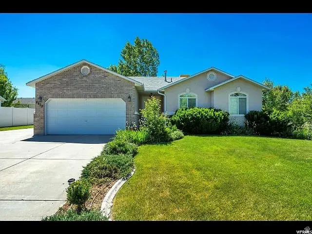 Ranch-style home with a garage, concrete driveway, a front lawn, and stucco siding