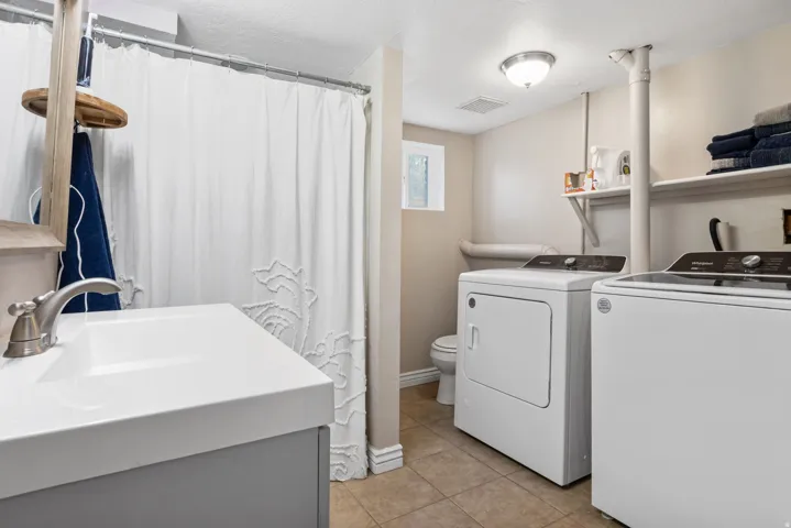 Laundry area featuring light tile patterned flooring, washing machine and clothes dryer, and a textured ceiling