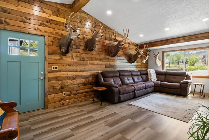 Living area with wooden walls, wood finished floors, beam ceiling, recessed lighting, and a textured ceiling