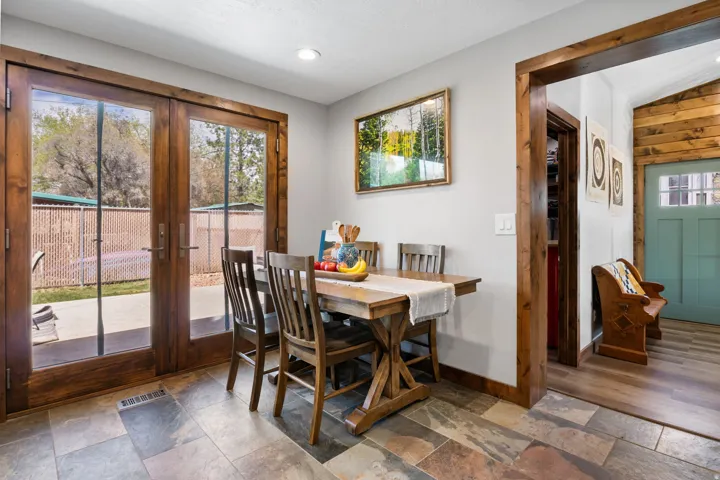 Dining room featuring stone tile floors, french doors, and lofted ceiling