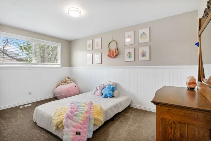 Bedroom featuring wainscoting and dark colored carpet