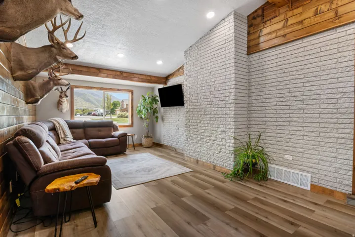 Living area with brick wall, wood finished floors, and recessed lighting