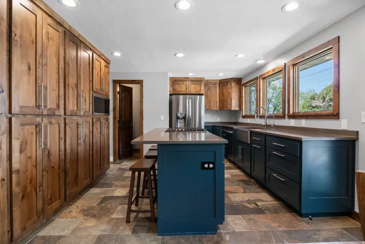 Kitchen with a breakfast bar area, recessed lighting, dark countertops, stainless steel appliances, and a center island