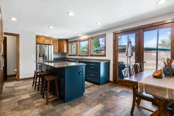 Kitchen featuring recessed lighting, a kitchen island, blue cabinetry, a breakfast bar, and dark stone finish flooring