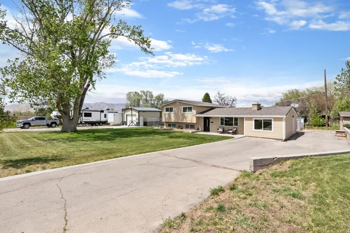 Split level home featuring concrete driveway, a front lawn, and a chimney