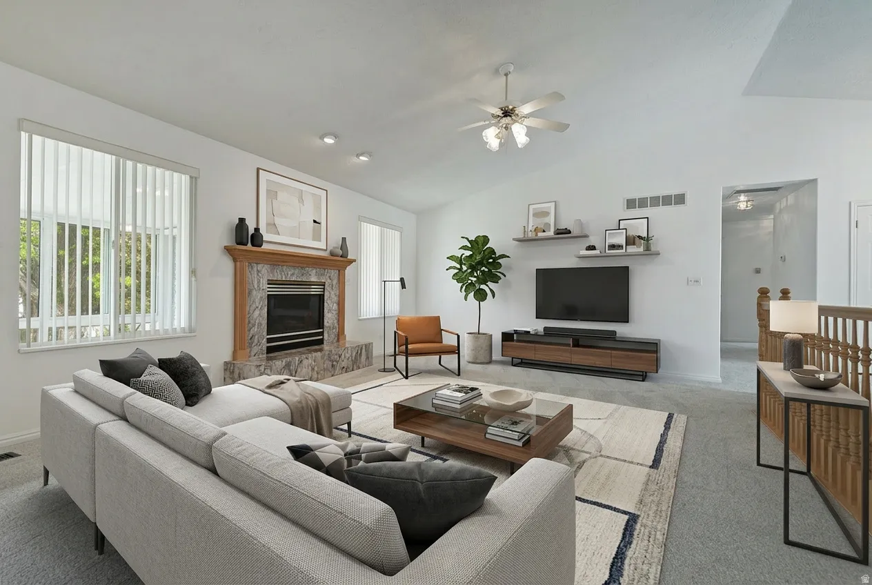 Living room featuring carpet, vaulted ceiling, ceiling fan, and a fireplace