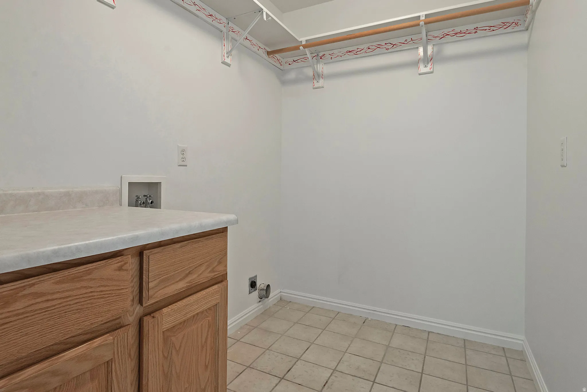 Laundry room featuring light tile patterned floors, washer hookup, and cabinet space