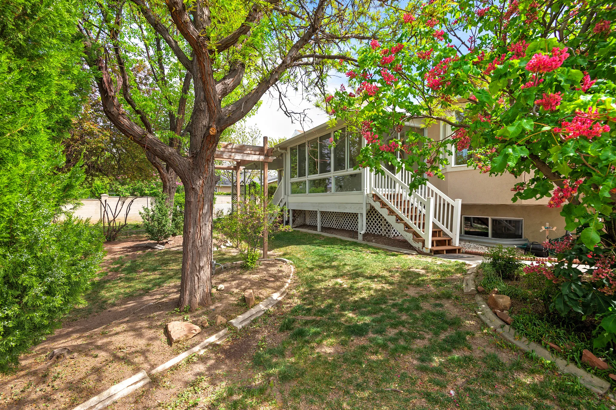 Back of property with a sunroom, a yard, a wooden deck, and stucco siding