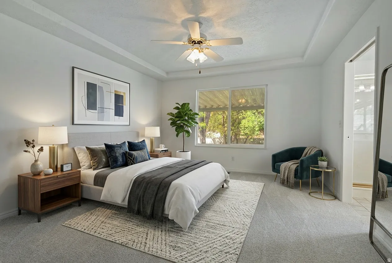 Bedroom with a raised ceiling, light colored carpet, and a ceiling fan