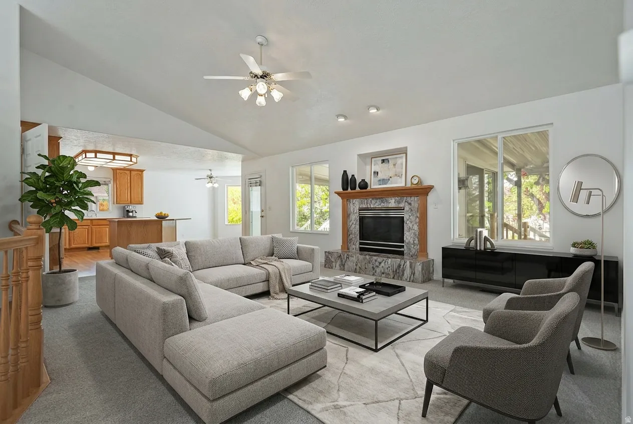 Living room featuring vaulted ceiling, a high end fireplace, ceiling fan, and light colored carpet
