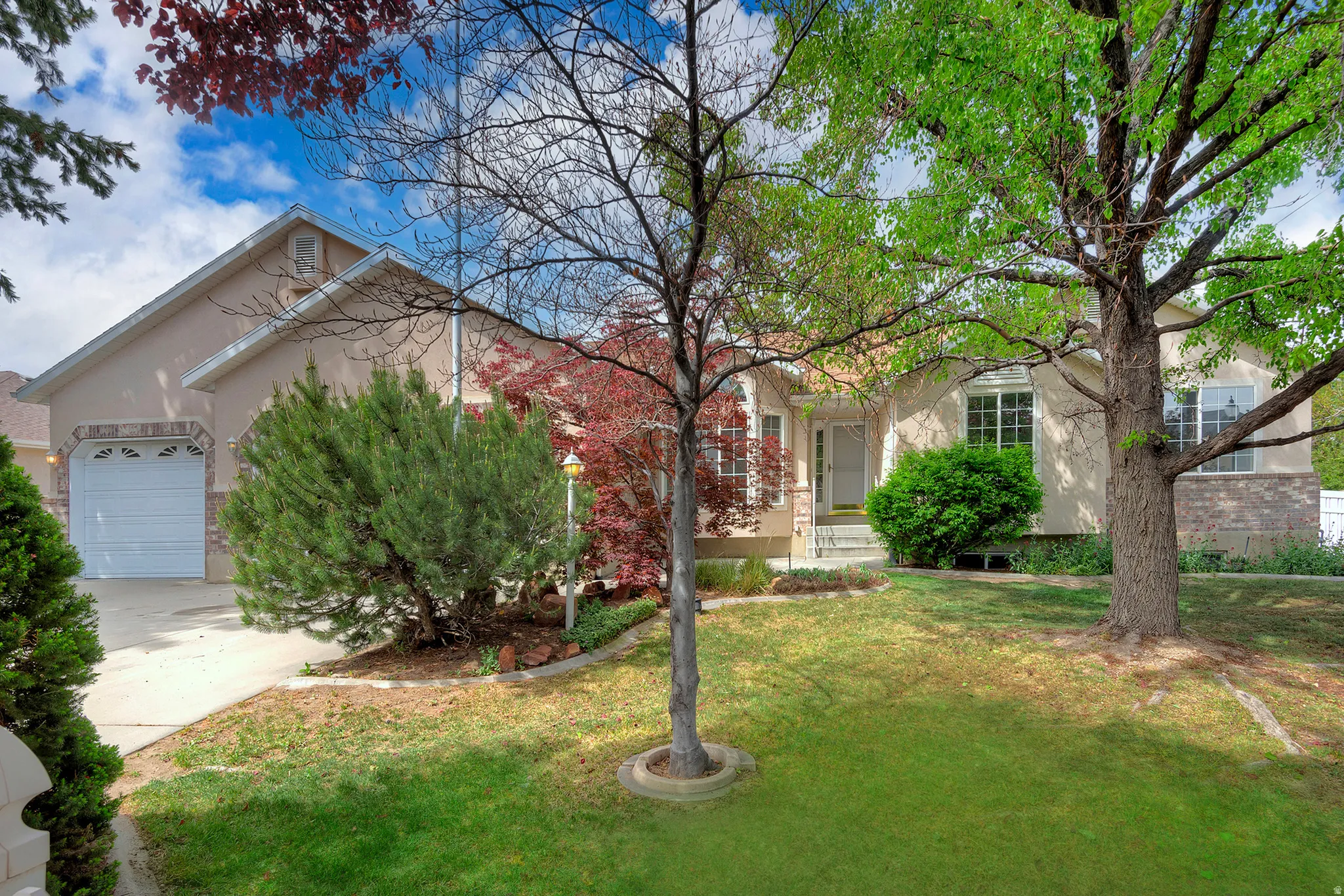 View of front of house with stucco siding, a front lawn, a garage, and concrete driveway