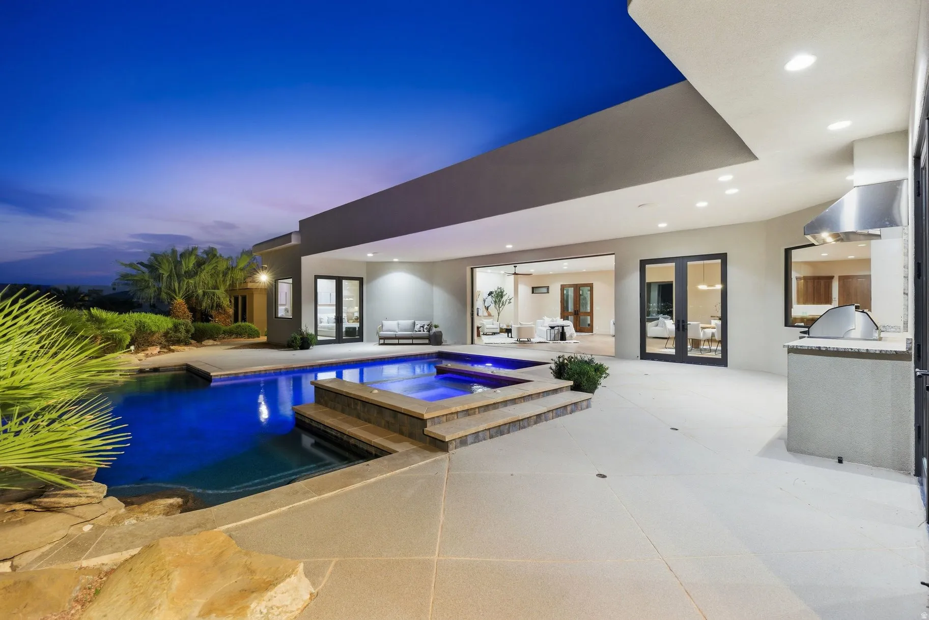 Relaxing pool / spa with french doors, an outdoor kitchen, and a patio area