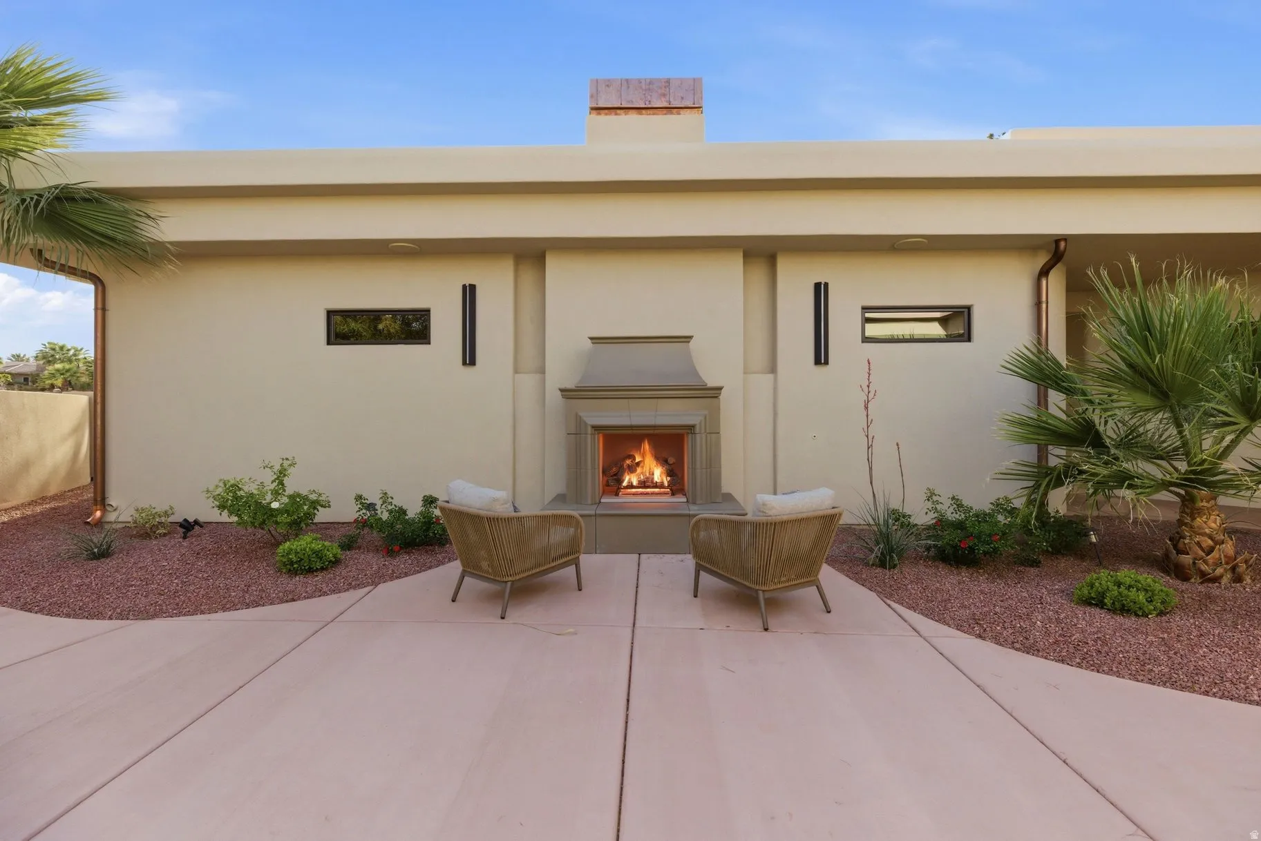 View of exterior entry featuring a warm lit fireplace, stucco siding, and a chimney