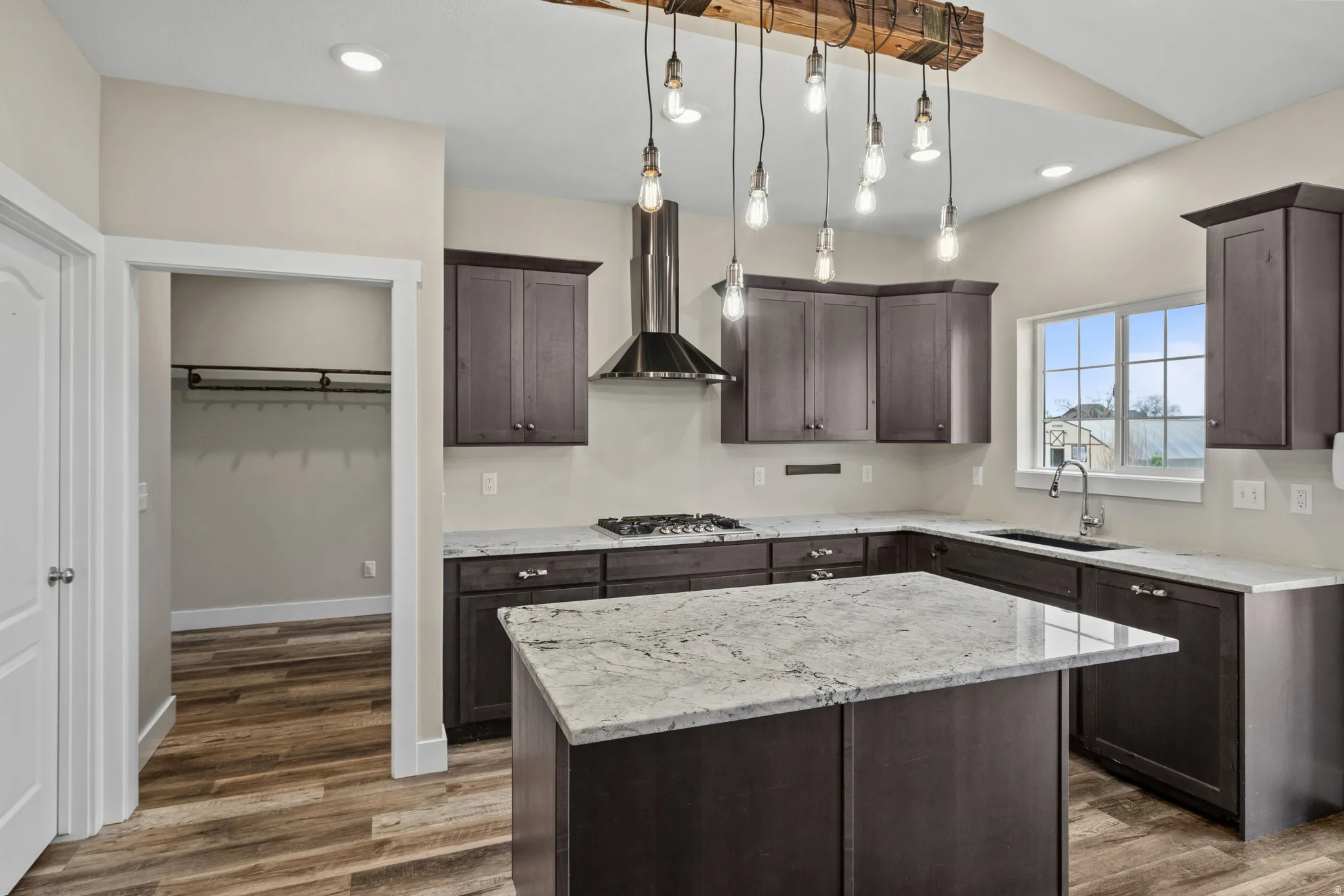 Kitchen featuring a center island, dark wood finish cabinets, decorative light fixtures, and dark wood-style floors
