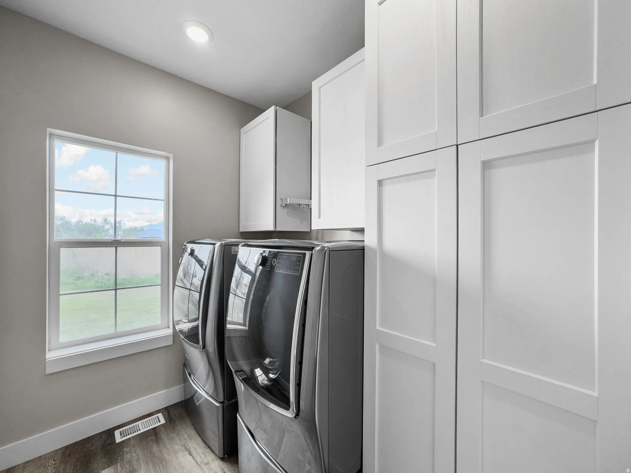 Laundry room with cabinet space, washer and dryer, light wood-type flooring, and recessed lighting