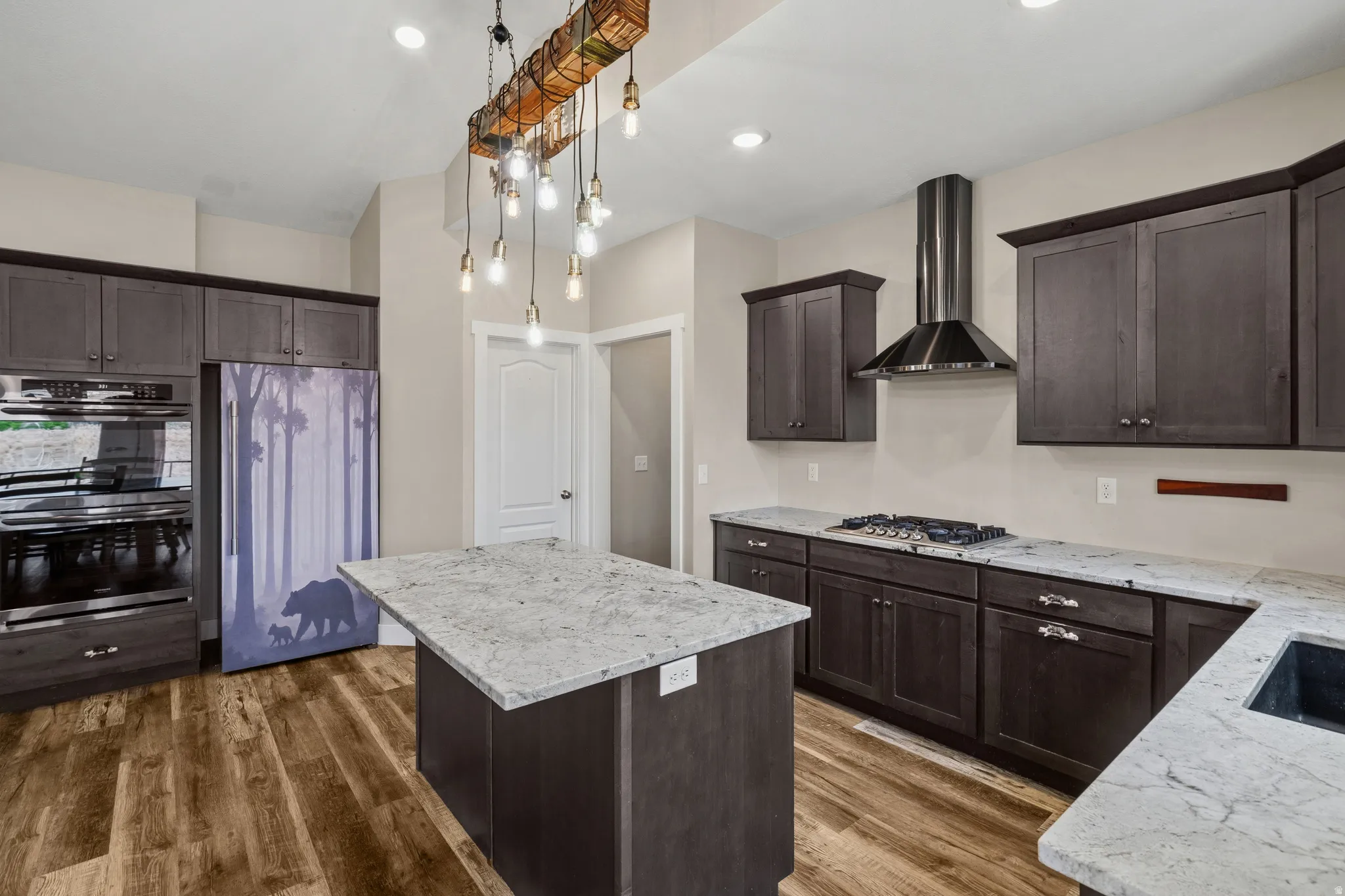 Kitchen featuring a kitchen island, stainless steel appliances, dark wood finish cabinets, and light stone countertops
