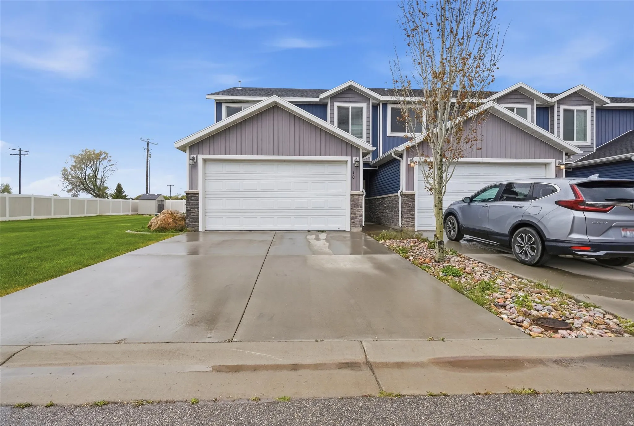 View of front facade featuring driveway, stone siding, and an attached garage