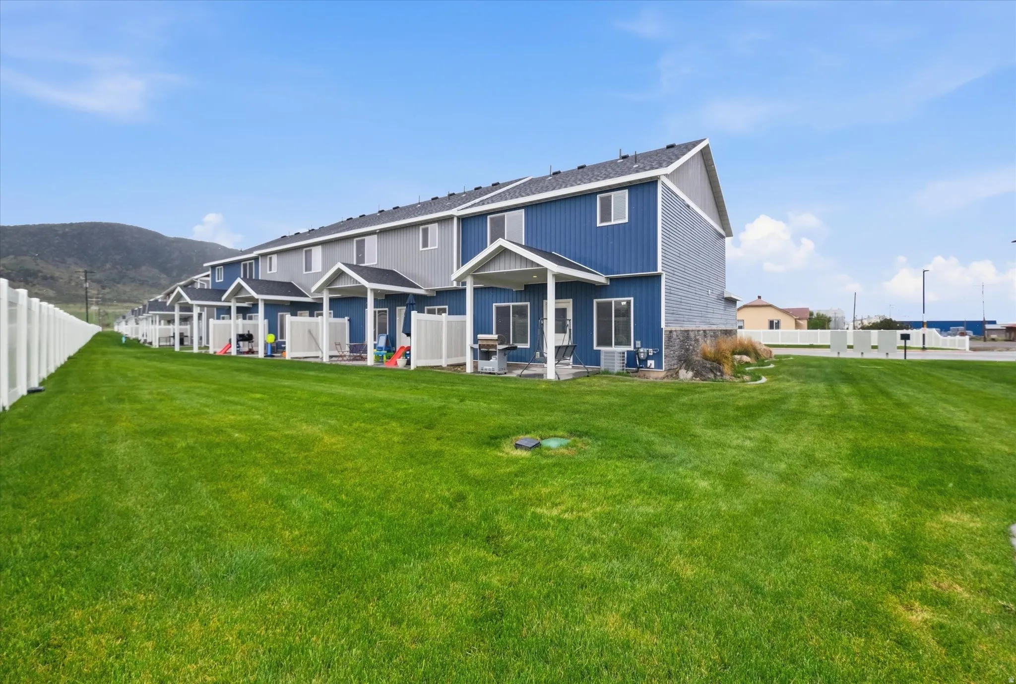 Back of house with a partially fenced backyard, a patio, a mountain view, and stone siding