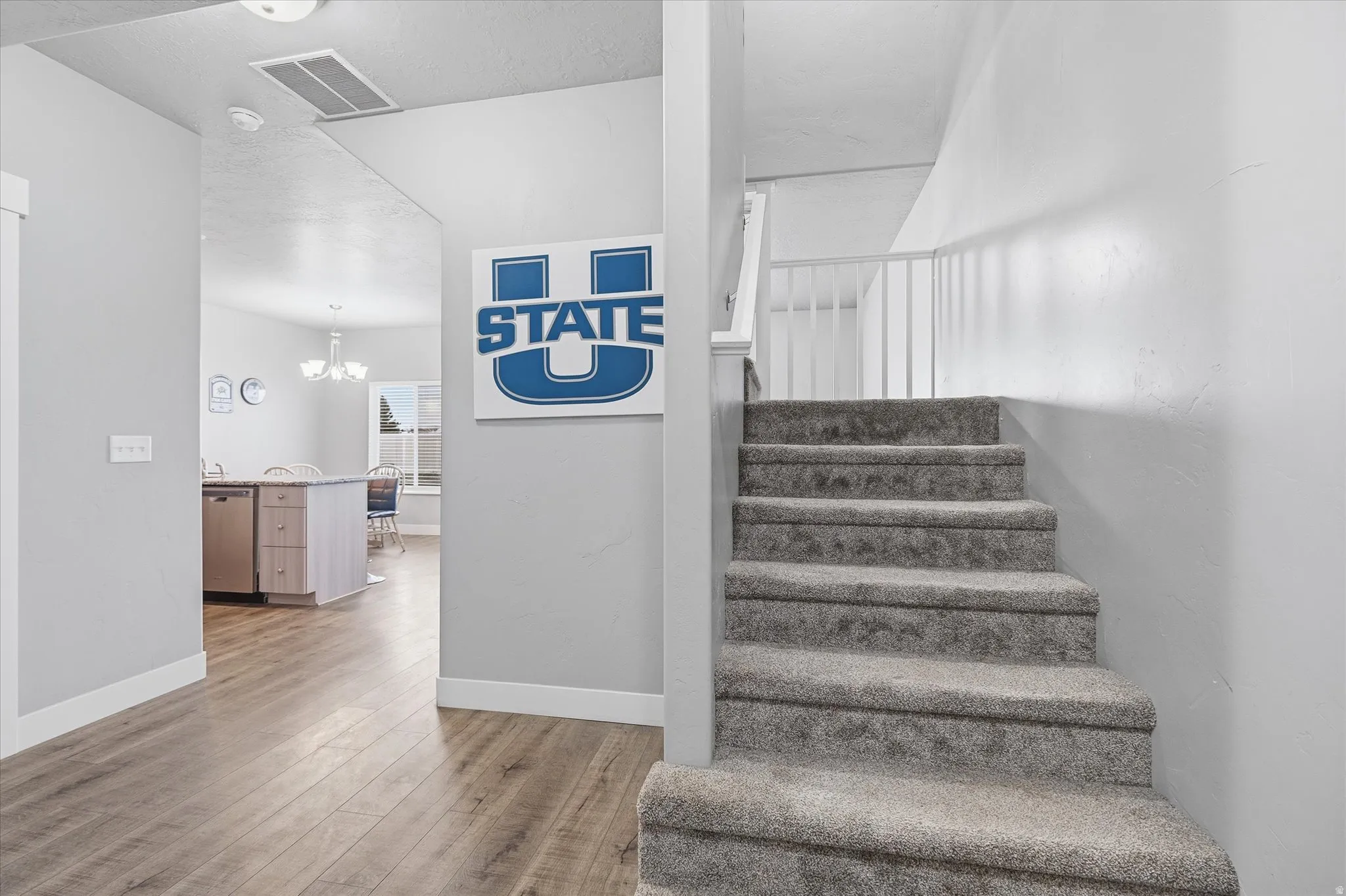 Stairway with hardwood / wood-style floors and suspended lighting